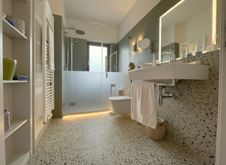 Modernes Badezimmer mit Glasdusche, Waschbecken und dekorativen Elementen in neutralen Farben.